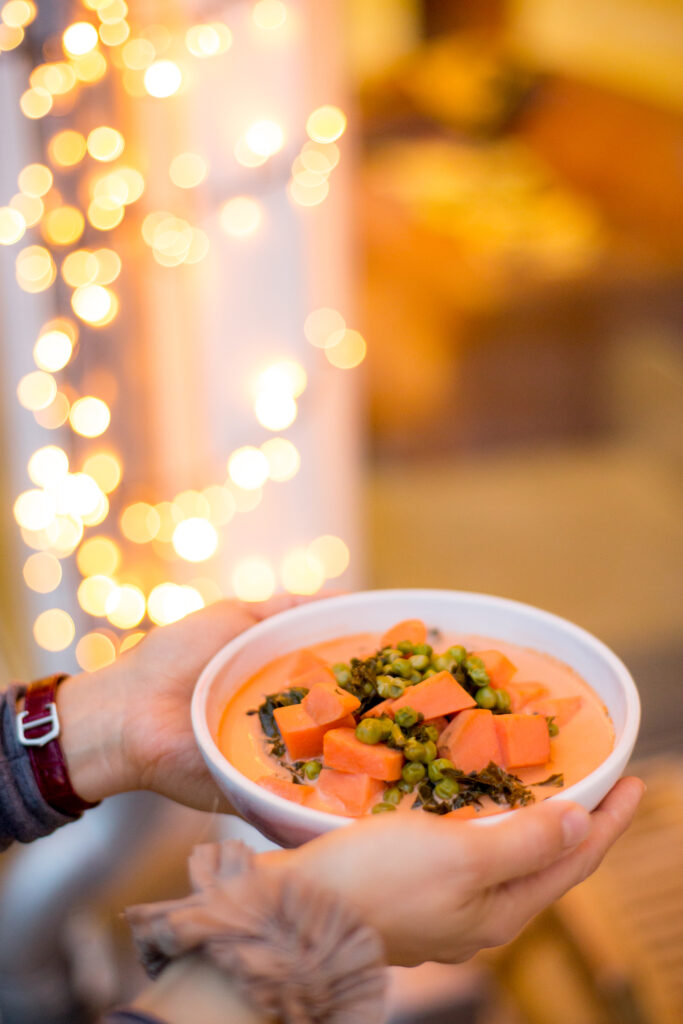 Schale mit hausgemachter Suppe vor weihnachtlicher Lichterkette