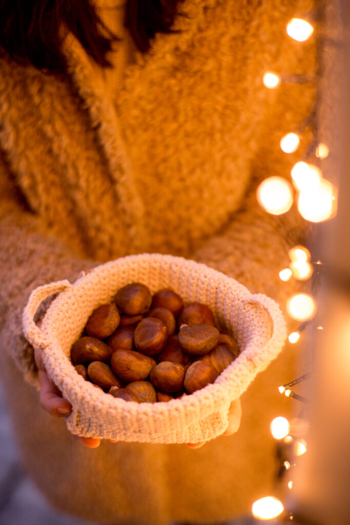 Korb mit Marroni vor weihnachtlicher Lichterkette
